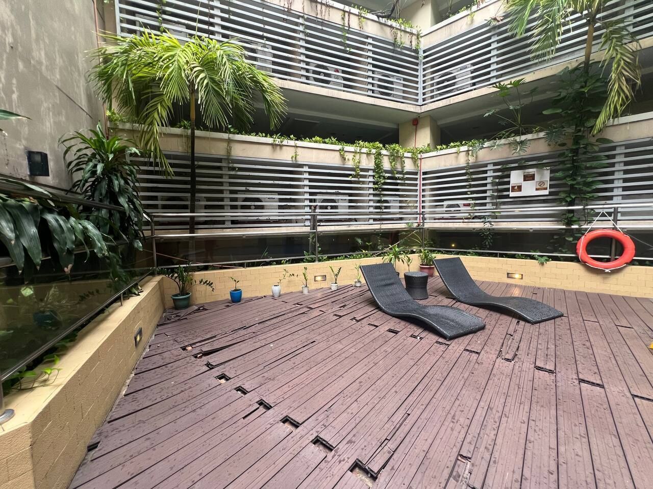 A rooftop deck with lounge chairs, potted plants, and a lifebuoy.
