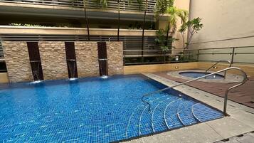 Una piscina con suelo de baldosas, rodeada por un muro de piedra y una barandilla de metal.