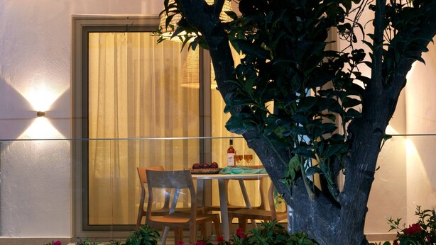 Un comedor con una mesa dispuesta para dos, una silla y una botella de vino.