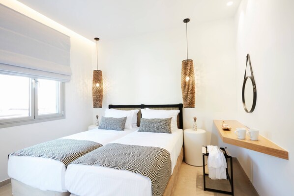 A modern hotel room with a large bed, two bedside tables, a small wooden shelf, and a window.