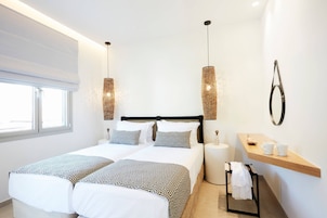 Una habitación de hotel moderna con una cama grande, dos mesitas de noche, un pequeño estante de madera y una ventana.