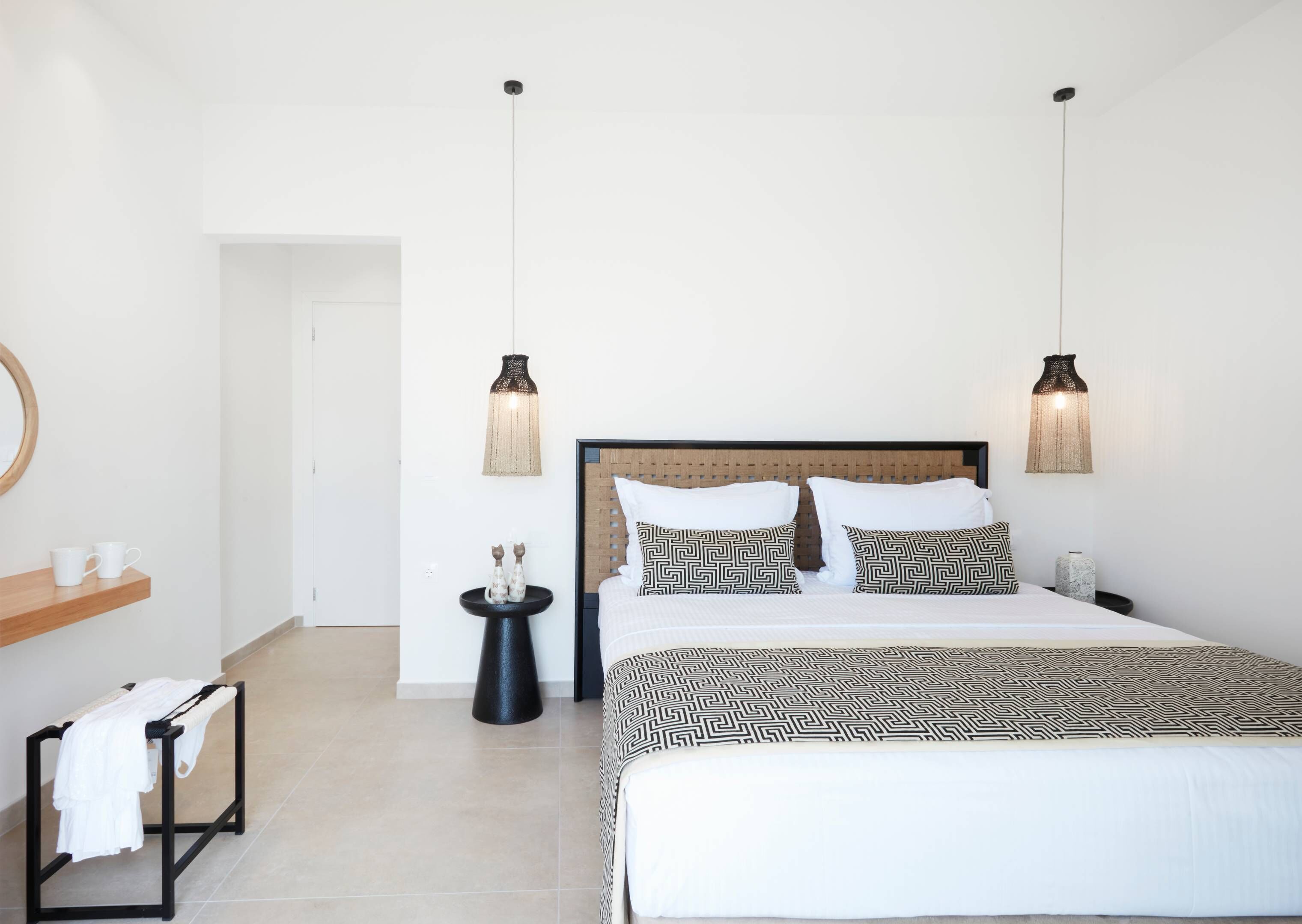 A hotel room with a bed, bedside tables, a mirror, and hanging lamps.