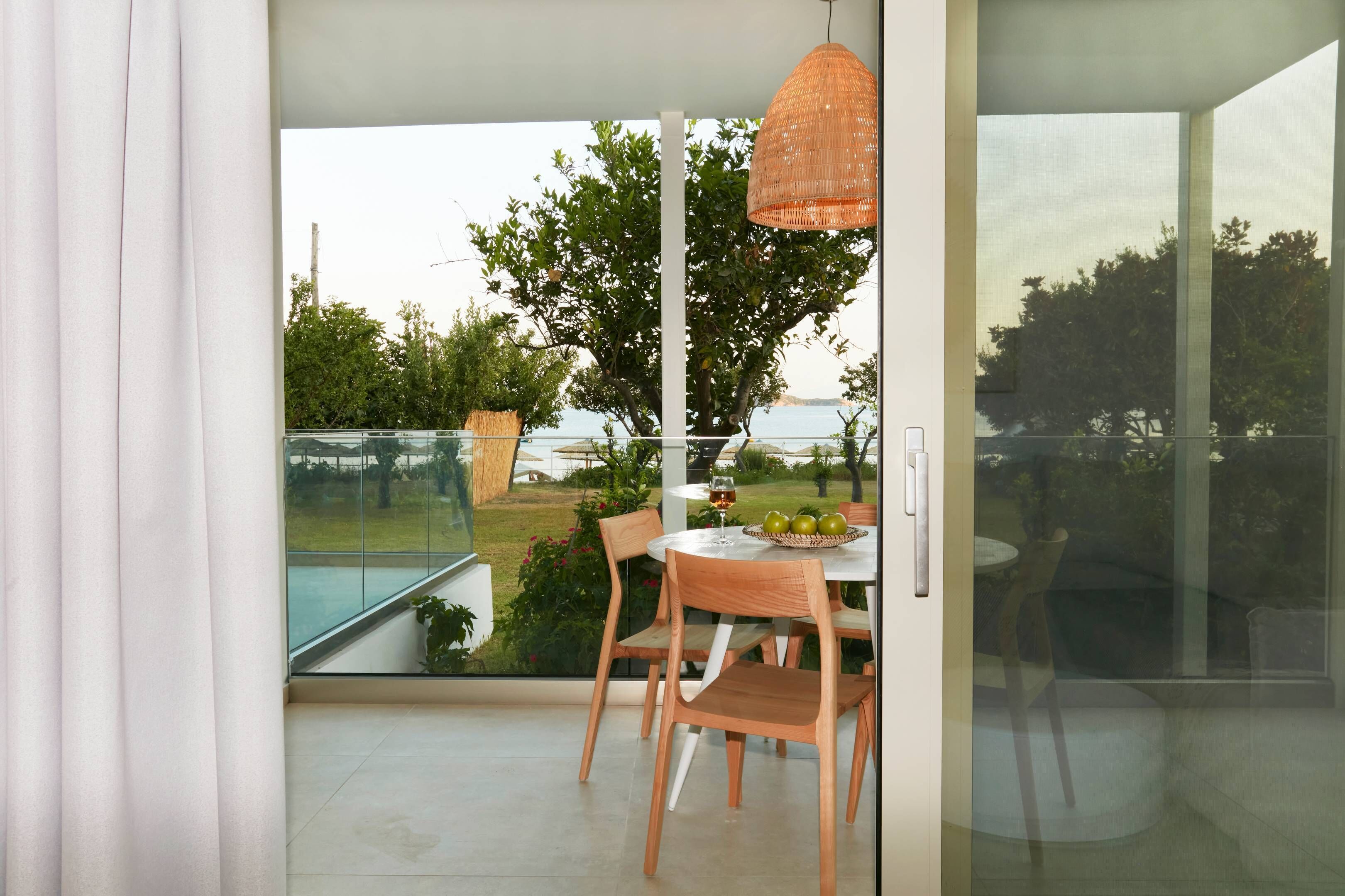 Habitación moderna con puerta de vidrio que da a un balcón con piscina, muebles de madera y una lámpara colgante.
