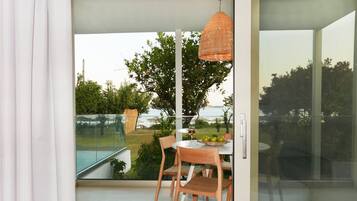 Habitación moderna con puerta de vidrio que da a un balcón con piscina, muebles de madera y una lámpara colgante.