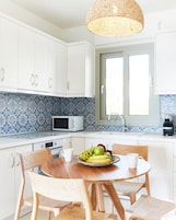 Una cocina moderna con armarios blancos, microondas, fregadero y una mesa de comedor con sillas.