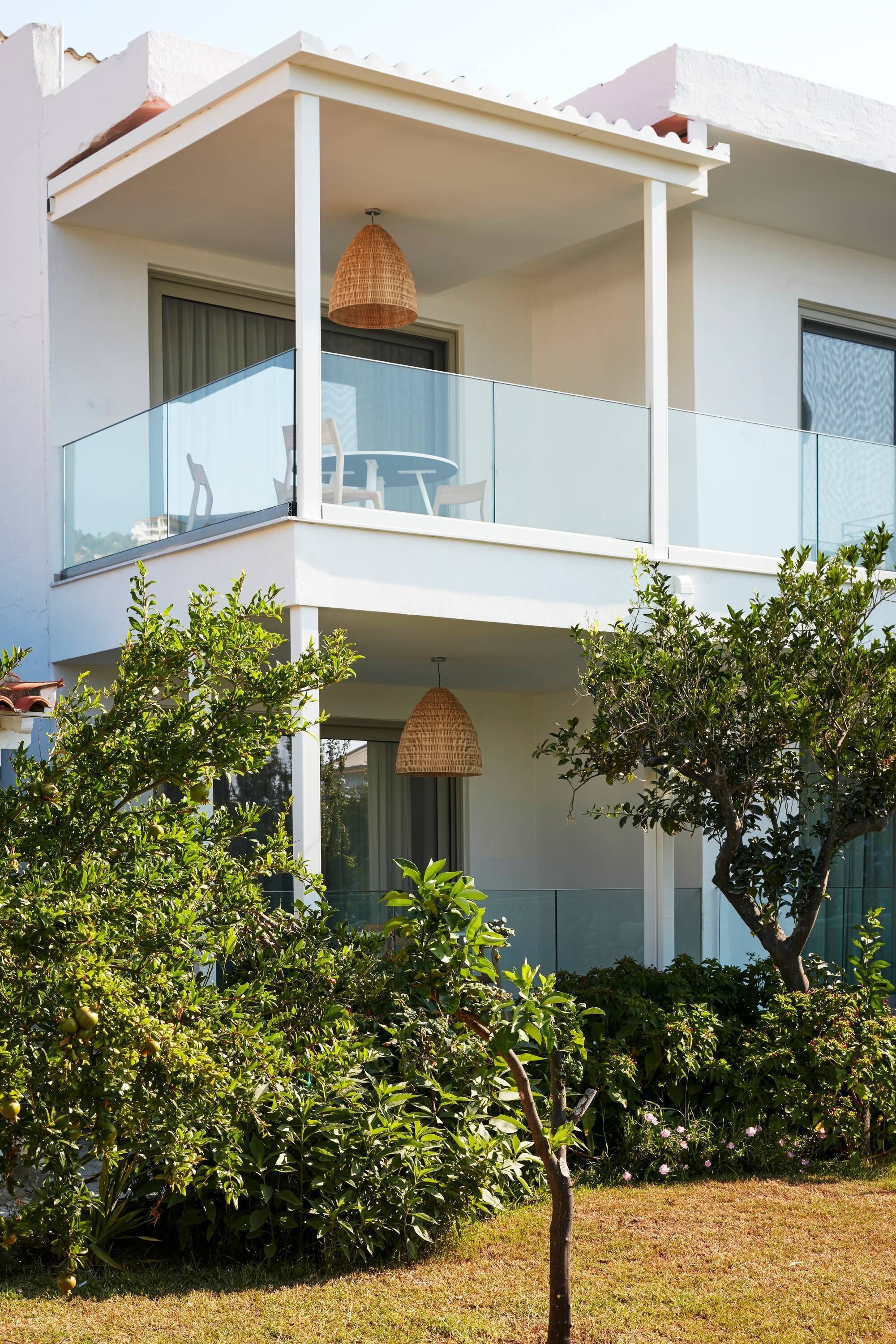Un edificio a due piani con un balcone, un lampadario e vegetazione circostante.