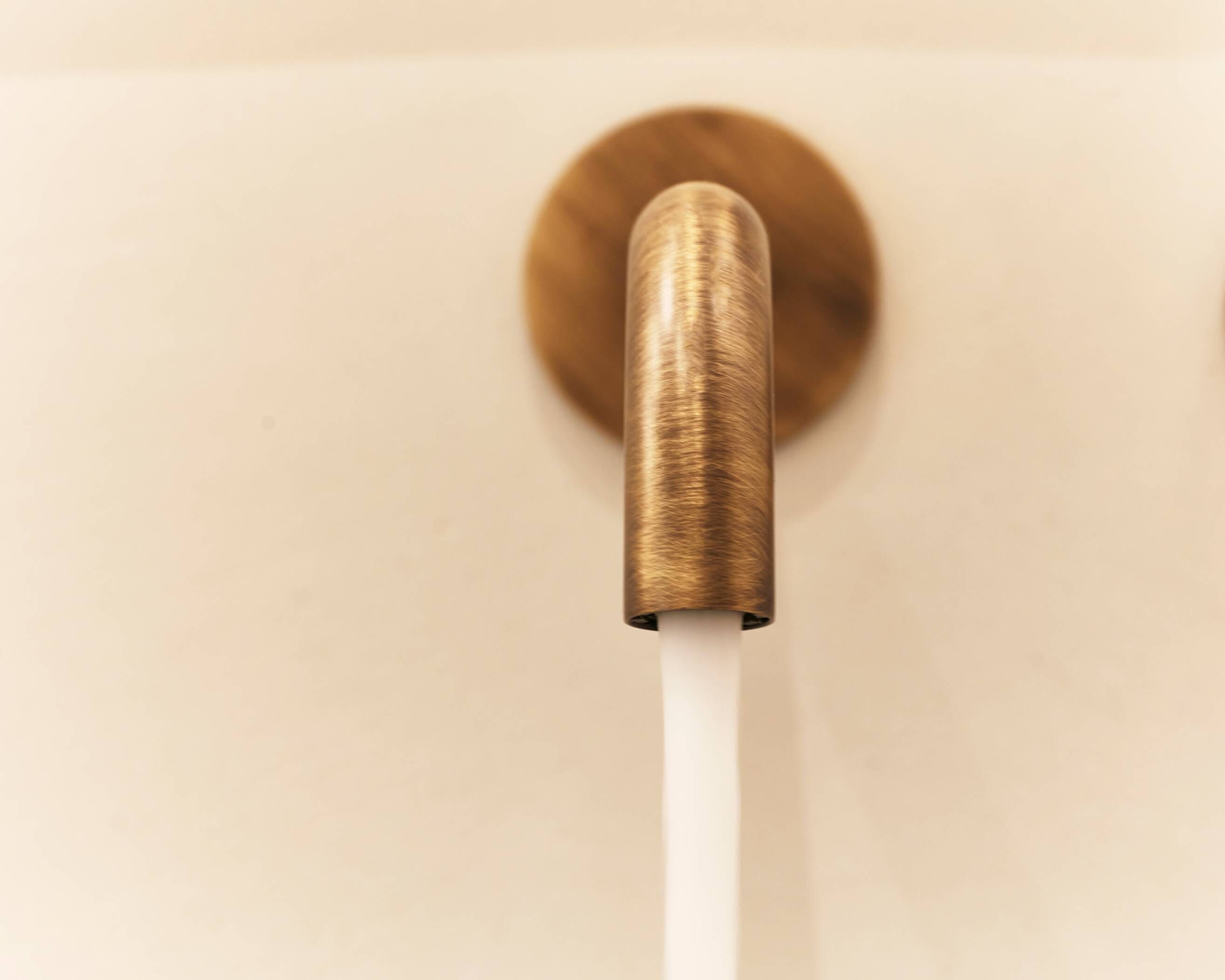 Um objeto cor de bronze com uma base cilíndrica branca, possivelmente parte de um móvel ou objeto de decoração.
