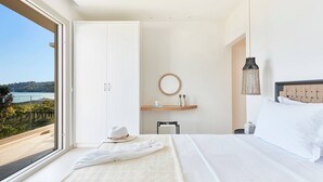 Un dormitorio con una ventana grande, una cama, una mesita de noche, una silla y vistas al exterior.