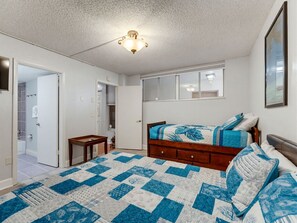 Un dormitorio con cama, mesita de noche, cómoda, ventana y puerta que da a un baño.