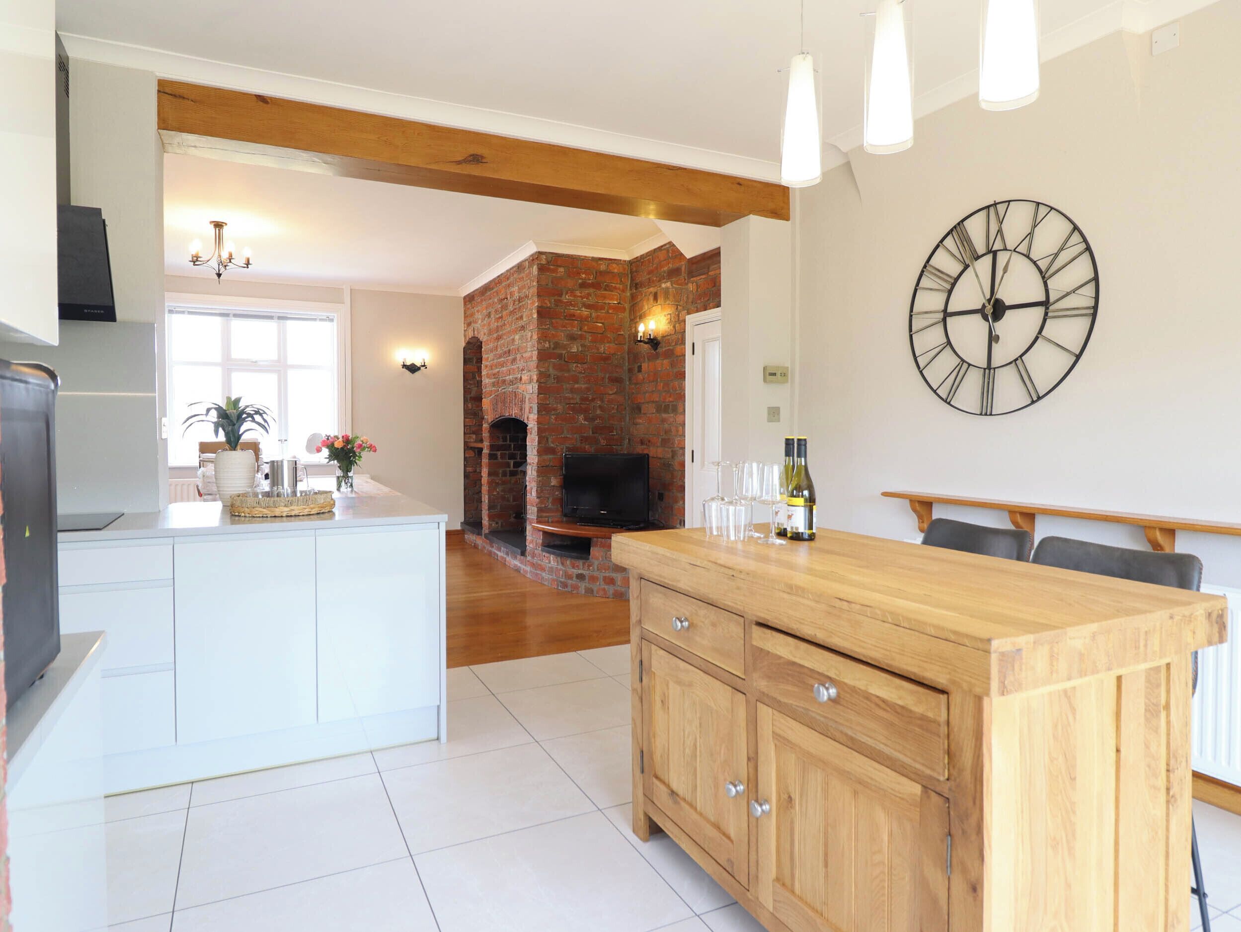 A modern kitchen with a central island, a brick fireplace, and a dining area with a wooden table and chairs.