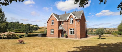A two-story brick house with a gabled roof, a front porch, and a well-maintained lawn.