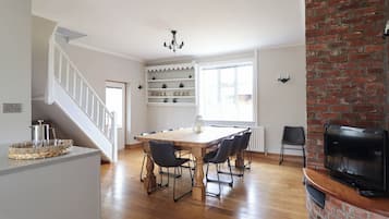 Un comedor con una mesa y sillas de madera, una araña y una chimenea de ladrillo.