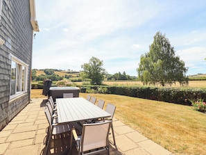 Un patio exterior con una mesa y sillas, un jacuzzi y vistas al paisaje rural.