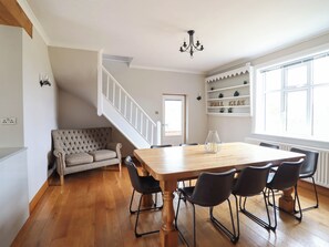 Un comedor con una mesa de madera, cuatro sillas, un sofá y una escalera.