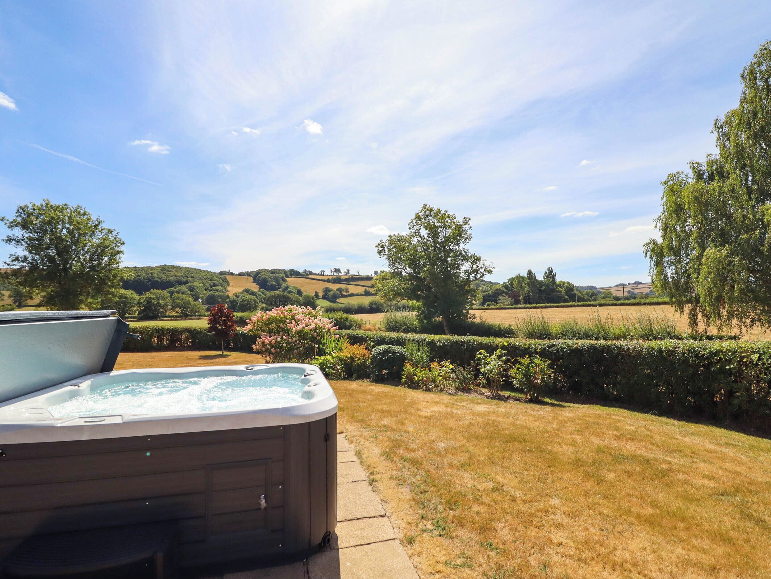 A hot tub in a garden with a view of rolling hills and trees.