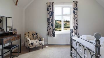A bedroom with a bed, a chair, a dresser, a mirror, and a window with curtains.