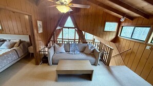 A cozy cabin interior with a bed, sofa, and a wooden table. - Serenity Now by Innsbrook Vacations! (Wright City)