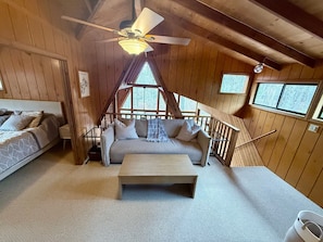 L’intérieur d’un chalet accueillant, avec un lit, un canapé et une table en bois.