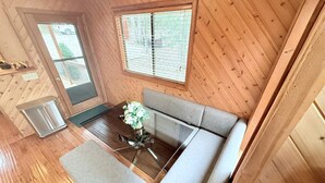A wooden-paneled room with a sofa, a glass-top table, and a bench. - Serenity Now by Innsbrook Vacations! (Wright City)