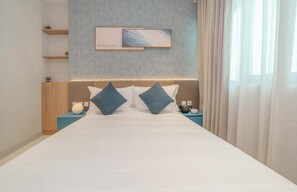 Ein Hotelzimmer mit einem großen Bett, zwei Kissen, einem Nachttisch mit Lampe, einem Telefon und einem Wandbild.