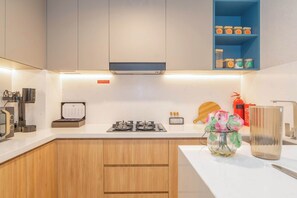 A modern kitchen with a gas stove, a coffee machine, and a shelf with jars. - Wellness Retreat with Infinity Pool, Gym & Sauna (Jumeirah Village Triangle)