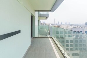 A narrow balcony with a glass railing overlooking a cityscape. - Wellness Retreat with Infinity Pool, Gym & Sauna (Jumeirah Village Triangle)