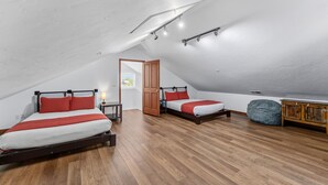 Un dormitorio con dos camas, suelo de madera y techo estilo loft.