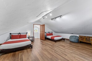 Ein Schlafzimmer mit zwei Betten, Holzboden und einer Schlafgalerie.