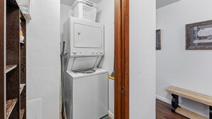 Un lavadero con lavadora, secadora y puerta de madera.