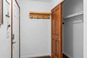 A room with a wooden door, a coat rack, and a white wall. - Frisco Mountain Condo | Fireplace, Garage and Great Location (Frisco)