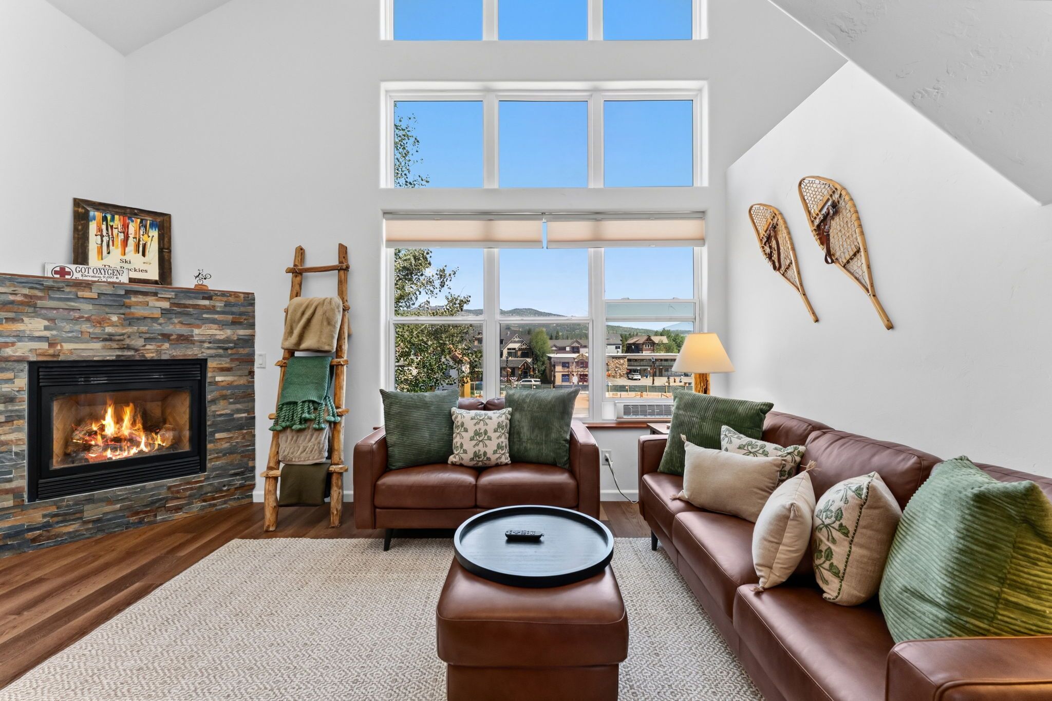 A living room with a fireplace, a sofa, a coffee table, and a view of a mountain landscape.