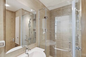 A modern bathroom with a glass-enclosed shower, a sink, and a mirror.