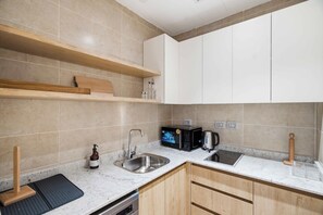 Une cuisine moderne avec un évier en acier inoxydable, un micro-ondes noir et des armoires en bois.