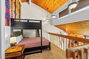 Une chambre à coucher avec un lit à baldaquin, une table de chevet avec une lampe et un tableau abstrait aux couleurs vives accroché au mur.