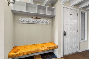 Ein Flur mit einer Holzbänkl, einer weißen Tür und einem an der Wand befestigten Kleiderhaken.