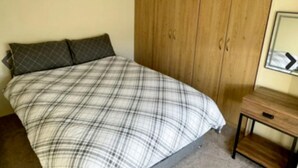 Une chambre à coucher avec un lit, une armoire en bois et une commode.
