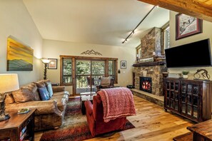 A cozy living room with a fireplace, leather furniture, and a stone accent wall. - Snowy Ski Basecamp | Fireplace, Shuttle to Slopes (Steamboat Springs)