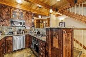 A kitchen with wooden cabinets, a stainless steel microwave, a gas stove, and a dishwasher. - Snowy Ski Basecamp | Fireplace, Shuttle to Slopes (Steamboat Springs)