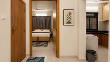 Une chambre d’hôtel comprenant un lit, une salle de bain, un coin cuisine et une porte donnant sur une autre pièce.