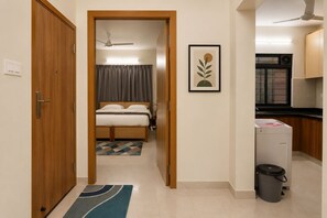 A hotel room with a bed, a bathroom, a kitchenette, and a door leading to another room. - Pinakii Comfort Stay Suites Prabhadevi (Mumbai)