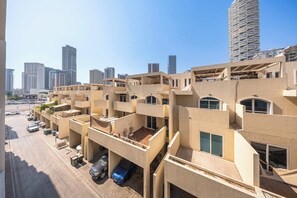 A multi-story residential building with balconies and a parking area in front. - StayShort - Contemporary Studio Sleeps 2 in JVC (JVC)