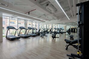 Ein Fitnessstudio mit Laufbändern, Kraftgeräten und Trainingsmatten.