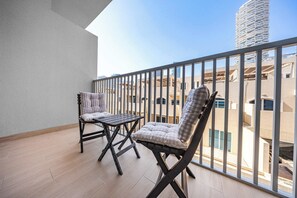 A balcony with two chairs and a table, overlooking a modern building with a unique cylindrical design. - StayShort - Contemporary Studio Sleeps 2 in JVC (JVC)