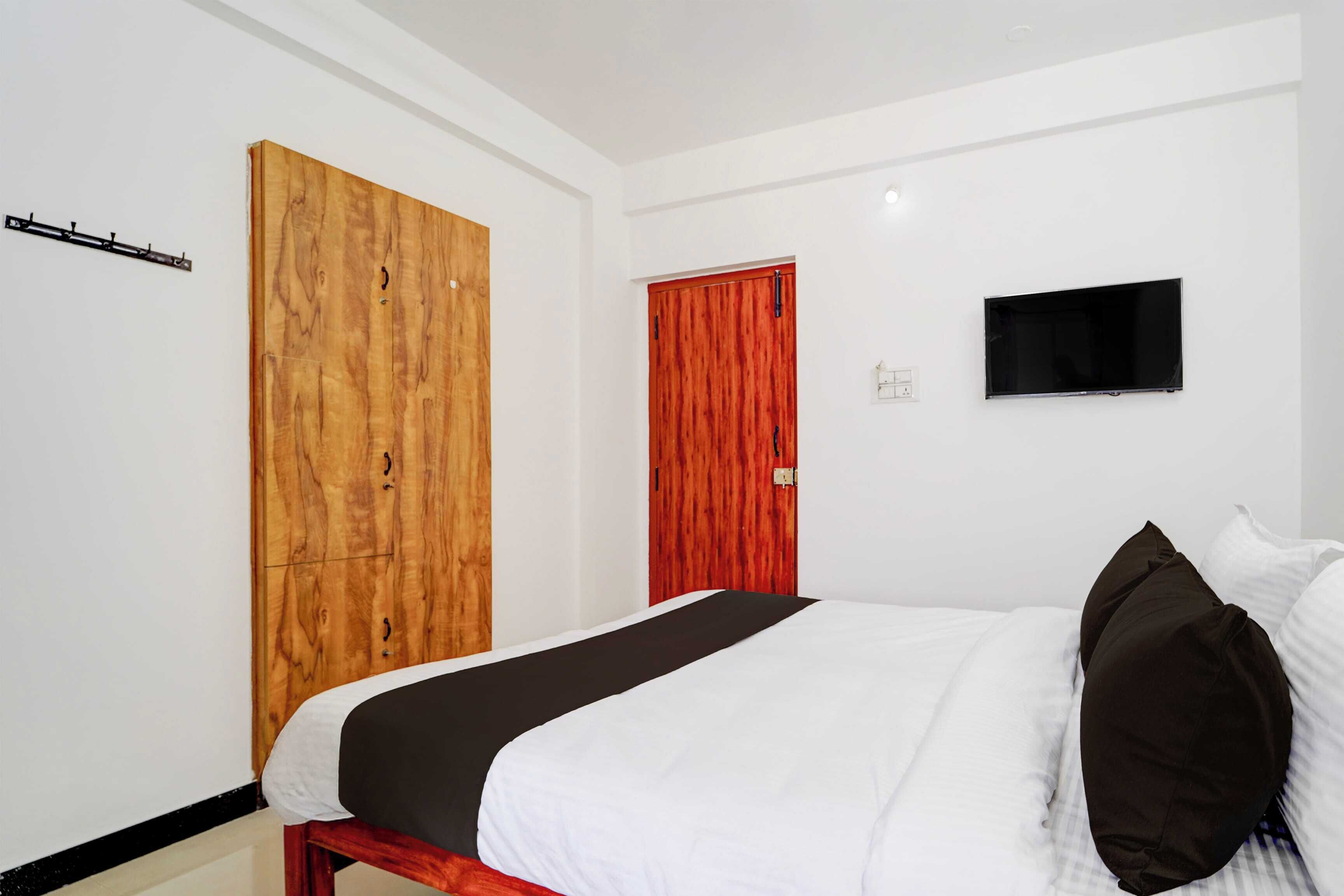 Un dormitorio con una cama, un televisor y dos puertas.