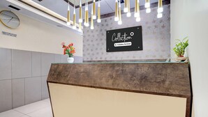 A reception desk with a clock, a sign indicating check-in times, and a floral arrangement. - Collection O Metro Park Opp Kalasipalya (Bangalore)