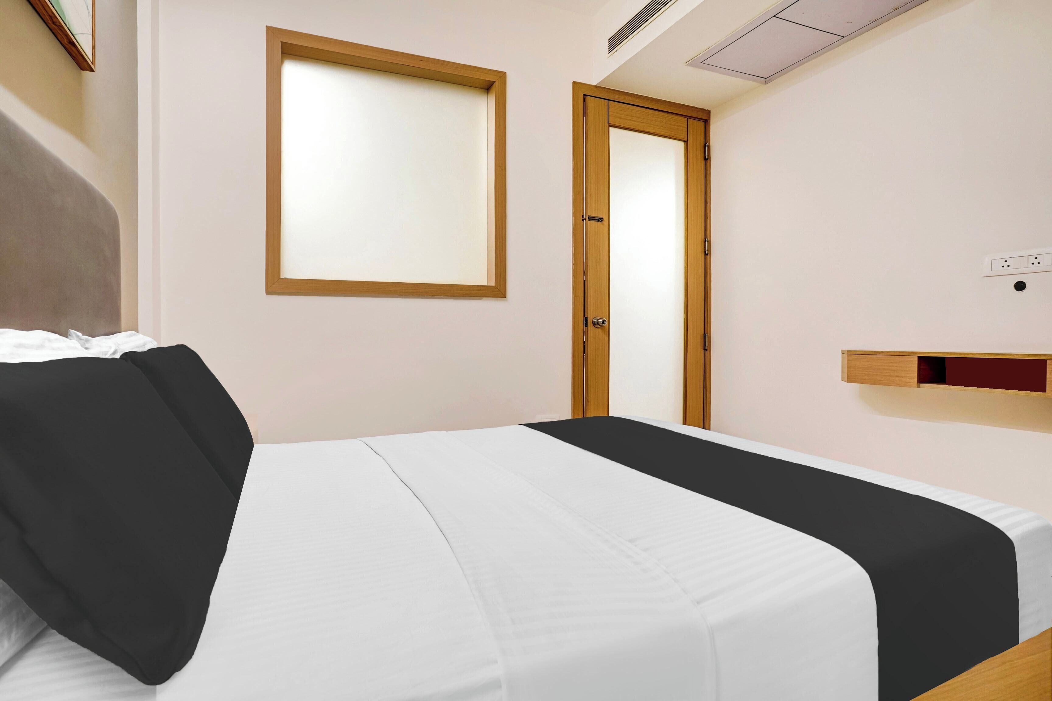 Un dormitorio con una cama, una ventana, una puerta y un pequeño estante de madera.