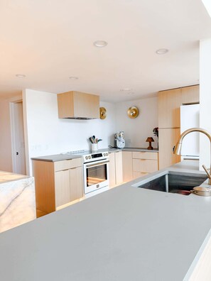 A modern kitchen with a central island, built-in oven, and stainless steel appliances.