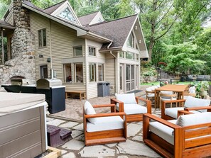 A two-story house with a stone chimney, outdoor seating area, and a stone patio.