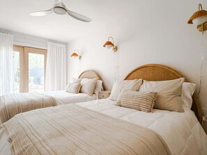 Ein Hotelzimmer mit zwei Betten, einem Deckenventilator und Wandlampen.