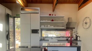 A modern kitchen with a central island, built-in appliances, and a dining area with a table and chairs. - Elmalı Guest House 
A simple, serene, and deeply peaceful life awaits you! (Muğla)